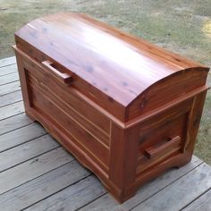 a large wooden box sitting on top of a wooden deck next to a grass field