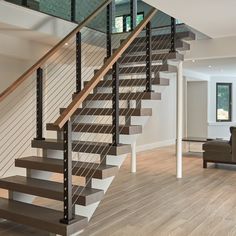 a living room filled with furniture and a stair case in front of a couch on top of a hard wood floor