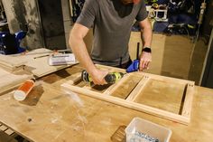 a man sanding wood on top of a wooden table with a drill and screwdriver