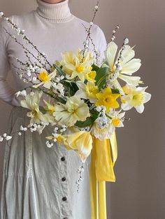 a woman holding a bouquet of yellow and white flowers