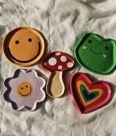 four different shaped cookies sitting on top of a white sheet with mushrooms, hearts, and smiling faces