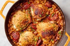 chicken and beans in a skillet on a white counter top with a yellow spatula