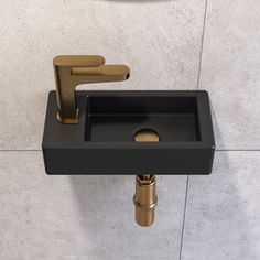 a bathroom sink with gold faucet and black counter top next to a mirror