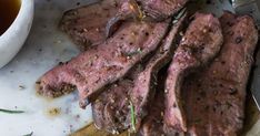 some meat is sitting on a cutting board next to a cup of tea and spoon