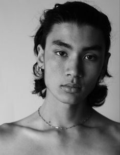 black and white photograph of a young man with no shirt on, wearing a necklace