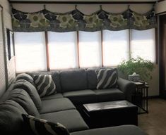 a living room filled with furniture and windows covered in shades on the window sill