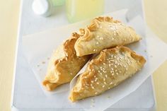 three pastries on a white plate next to two bottles with lemonade in them