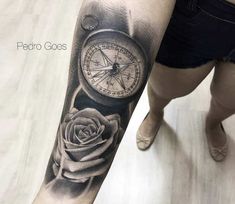 a woman's arm with a rose and an old compass tattoo on the forearm