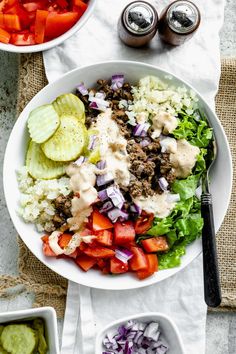 two bowls filled with different types of food on top of a white table cloth next to silver spoons