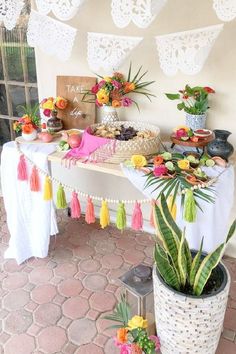 a table topped with lots of food next to a potted plant on top of a stone floor