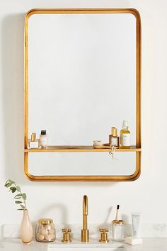 a bathroom sink with gold fixtures and a large mirror above it, on a white wall