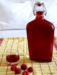 a bottle of red wine sitting on top of a table next to a glass filled with liquid