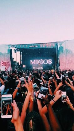 many people are holding their cell phones up in the air at an outdoor music festival