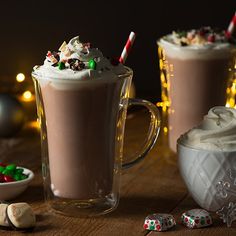 two mugs filled with hot chocolate and marshmallows on a wooden table