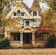 an old victorian style house in autumn with leaves on the ground and trees around it