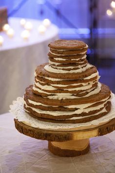 a large stack of cookies sitting on top of a wooden cake plate with frosting