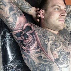 a man sitting in a chair with tattoos on his arm