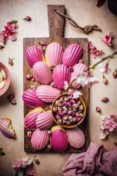 some food is laying out on a cutting board with pink flowers and petals around it