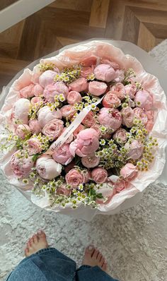 a large bouquet of pink roses is sitting on the floor next to someone's feet