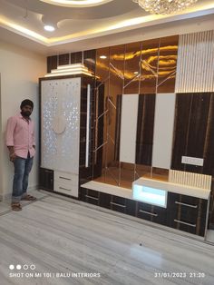 a man standing in front of a large mirror with lights hanging from it's sides