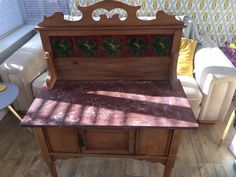 a small wooden table with a mirror on it's top and some chairs in the background