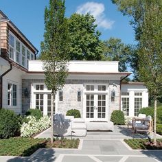 an outdoor patio with chairs and trees in front of the house on a sunny day