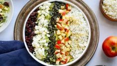 a bowl filled with rice, fruit and nuts next to two bowls full of salad