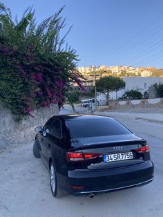 an audi car parked in front of a stone wall with flowers growing on it's side