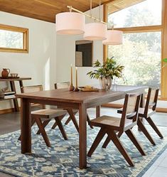 a dining room table with four chairs and a potted plant