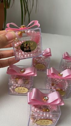 pink pearls and bows are in small clear boxes with gold accents on the top, along with personalized tags