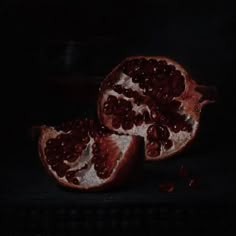 two halves of a pomegranate on a black surface