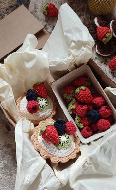 crocheted strawberries are in small baskets on the table next to other items