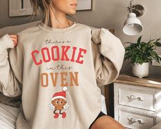 Are you looking for a trendy pregnancy Christmas sweatshirt for yourself or for someone you love? If that's the case, you're in the right place. This cute sweater, with a cute baking design, is meant to put a smile on your face every time you wear it and to help you deliver the great news of a baby on the way in a much jollier way. If you know someone who is pregnant and loves wearing Christmas themed clothes, this sweatshirt would make a great present for her.  Check out more pregnancy themed designs in our shop: https://www.etsy.com/shop/AllTheHappyDesigns?ref=seller-platform-mcnav&section_id=51347032 PRODUCT DETAILS AND SIZING UNISEX SWEATSHIRT. Please see the last pictures for measurements. 50% cotton, 50% polyester no side seams ribbed knit collar with seam Ideal for any situation, a Pregnancy Christmas Sweater, Baking Design, Christmas Baby Announcement, Christmas Pregnancy Announcement, Christmas Pregnancy, Present For Her, Cute Baking, Pregnancy Reveal, Presents For Her