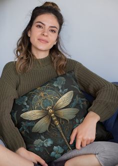 a woman sitting on a couch holding a pillow with a dragonfly design on it