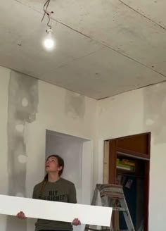 a woman standing on top of a ladder in a room that is being renovated with white paint