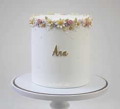 there is a white cake with flowers on the top and an arn written in gold