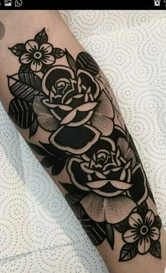 a black and white rose tattoo on the arm is shown with flowers in blooming around it