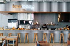 the inside of a restaurant with wooden tables and stools in front of an open kitchen