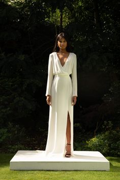 a woman standing on top of a white platform in front of some trees and grass