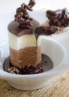 there is a piece of cake with chocolate and nuts on the top, sitting on a white plate