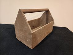 an old wooden box sitting on top of a black cloth covered table with a white wall in the background