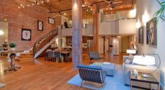 a living room filled with lots of furniture and a staircase leading up to the second floor