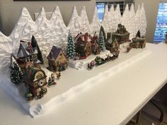 a white table topped with lots of snow covered trees and houses on top of it