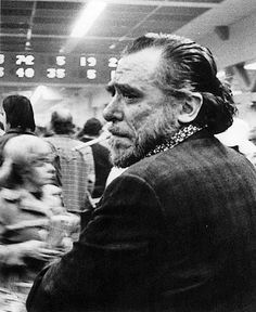 black and white photo of man with beard in crowd at indoor event looking off to the side