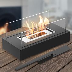 a glass fire pit sitting on top of a wooden table