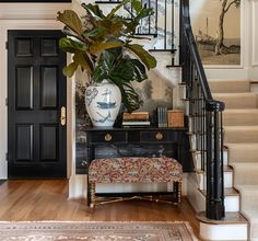 a plant in a vase on top of a table next to a stair case and rug