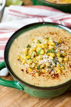 a green bowl filled with soup on top of a wooden table