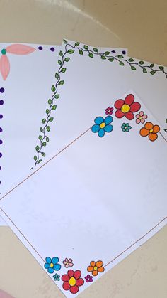 two notebooks with flower designs on them sitting on a table next to each other