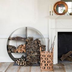 a fireplace with logs in front of it and a mirror on the wall behind it