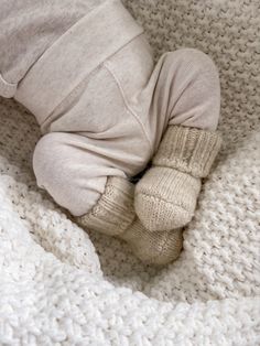 a baby is laying down on a blanket with his feet tucked under the edge of it